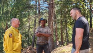 CalFire official talking on back road with a crew manager and nonprofit staff member